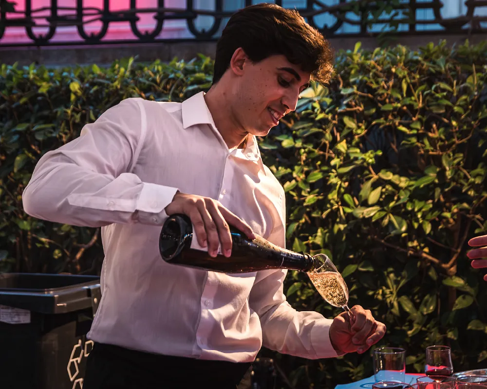 Kellner gießt ein Glas Champagner ein